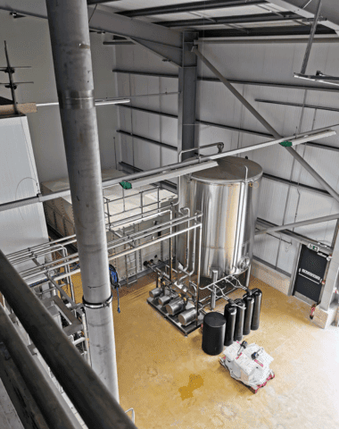 Plant room seen from a mezzanine, with stainless tanks and pipework