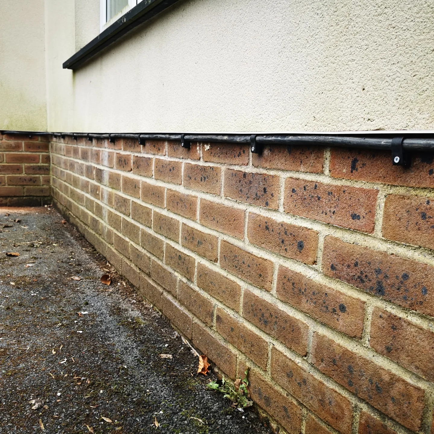 Cable run clipped along the base of the house wall