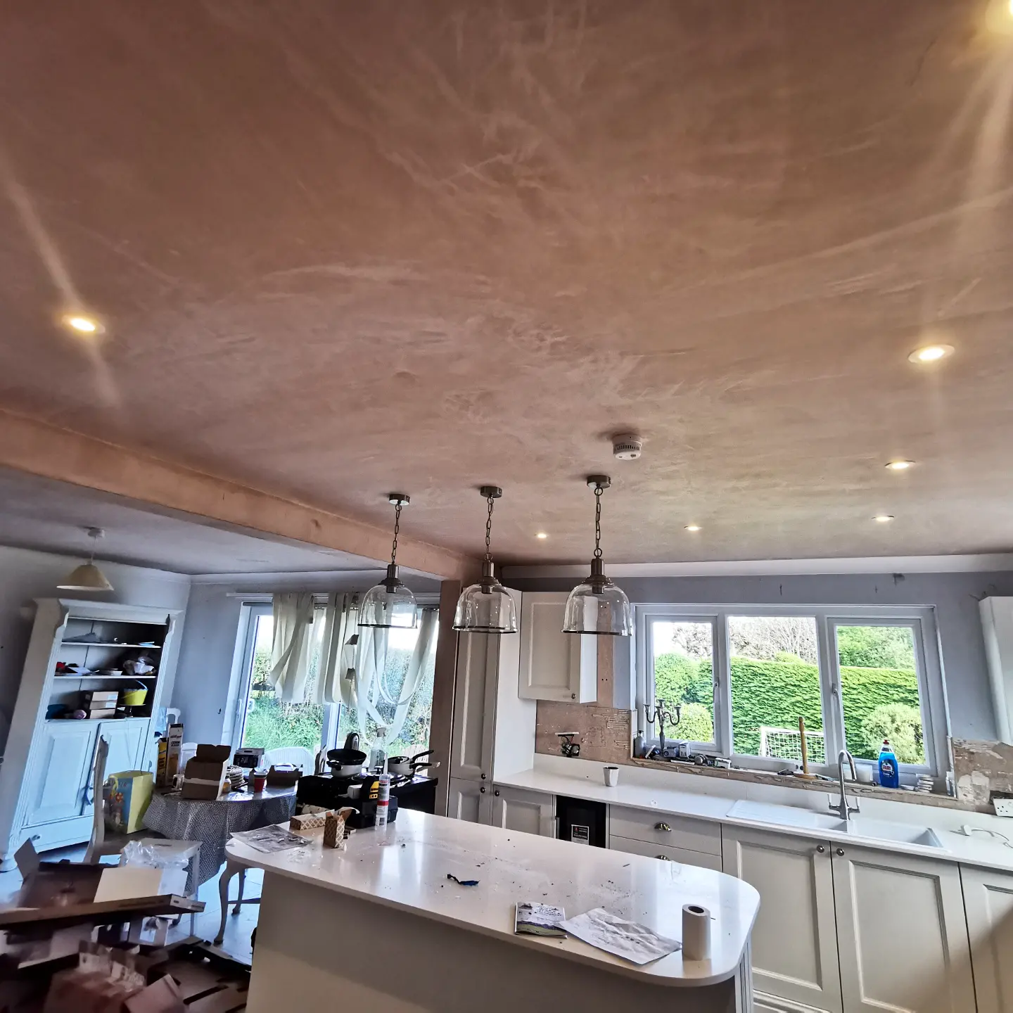 The kitchen after, with down lights and three pendants over the island